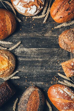 Bread border on wood background with copy space. Whole grain loaves with spikelets. Different types...