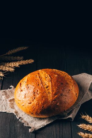 Loaf of brown bread on textile towel on black wooden background with copy spaceの写真素材