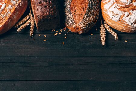 Bread border on dark wood background with copy space. Different kinds of bread. Bakery, cooking and grocery store concept.の写真素材