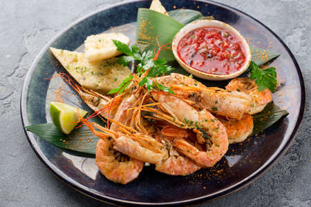Grilled tiger shrimp with parsley, red sauce, toast and lime on plateの写真素材