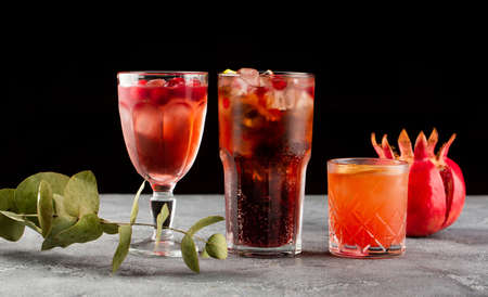 Set alcoholic cocktails with delicious fruits. Cocktails with eucalyptus leaves and pomegranate on black backgroundの写真素材
