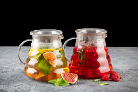 Set of fruit and berry teas in glass teapots on dark background on gray tableの写真素材