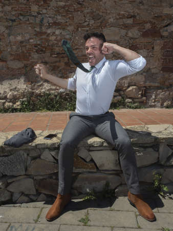 man with a victory attitude, celebrating happily with his tie in motion and his mouth wide openの写真素材