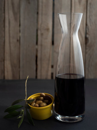 elongated wine decanter with an olive aperitif and an olive branch, wooden plank backgroundの写真素材