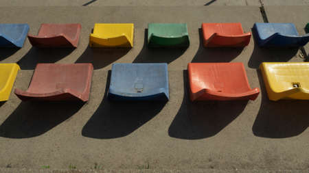 row of seats of a grandstand, colored seats, horizontal photograph with pronounced shadows