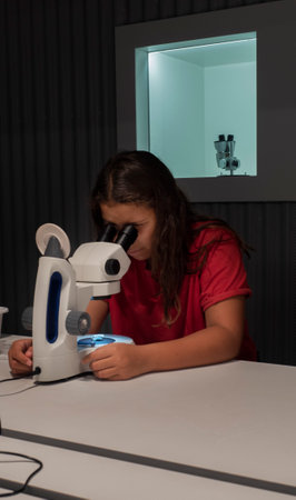 A pre-teen student looks at a rock through a microscope.の写真素材