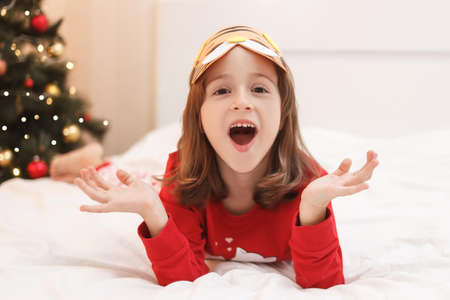 funny girl with beautiful blue-orange eyes in a cardboard mask in the form of a tiger plays at home....