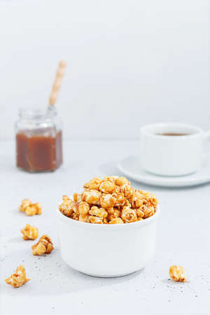 Sweet caramel popcorn in a ceramic bowl on a gray backgroundの写真素材
