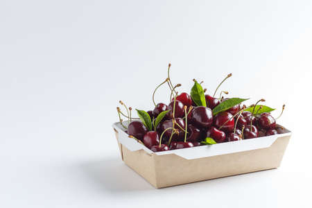 Fresh, ripe cherries in a cardboard box on a white background. copy spaceの写真素材