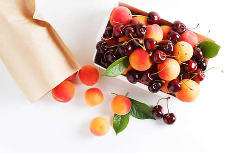 Apricots and cherries in paper packaging on a white background. the concept of eco-friendly packaging without plastic. top viewの写真素材