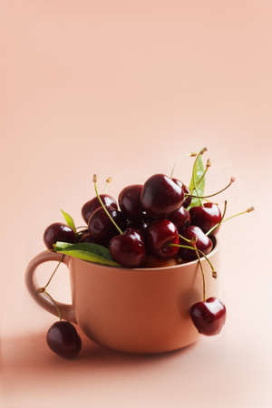 Fresh, ripe cherries in a ceramic mug on a beige background. copy spaceの写真素材