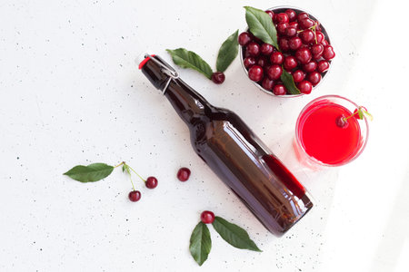 Cold cherry juice in a glass and bottle with ripe berries. Top view, copy space for text. The concept of summer refreshing drink morse or kompot.の写真素材
