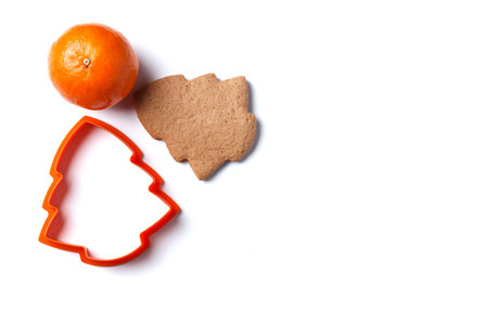 Ready-made Christmas cookies in the form of a Christmas tree with a cookie cutter and a tangerine isolated on a white background. copyspace.の写真素材