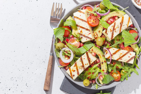 Salad with fried Halloumi cheese, cherry tomatoes, arugula and pomegranate seeds. healthy food. copy spaceの写真素材