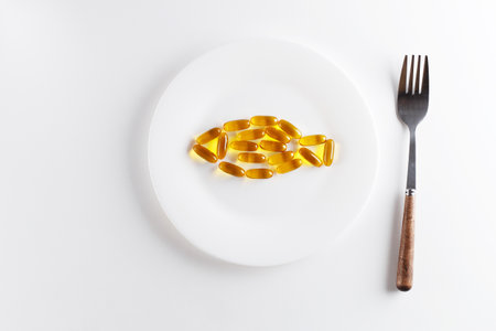 Omega-3 capsules on a fish-shaped plate on a white background. The concept of nutritional supplements and healthy nutrition. copy spaceの写真素材