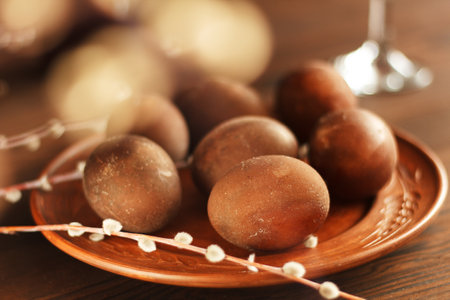 painted eggs on a plate with a sprig of willow on a wooden table. Easter celebration.の写真素材