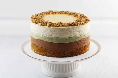 Pistachio cake on a stand on a gray background. Ingredients: pistachio sponge cake, pistachio...