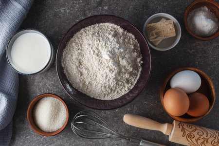 Preparation for baking. Eggs, sugar, milk, flour, salt, yeast, rolling pin, whisk on the kitchen...