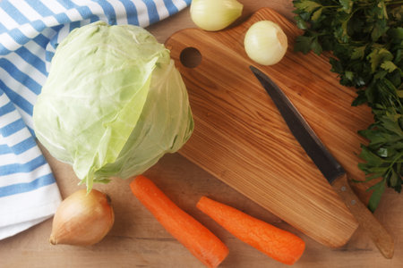 Cabbage lies on a wooden board with carrots, onions and herbs. Preparing to cook cabbageの写真素材