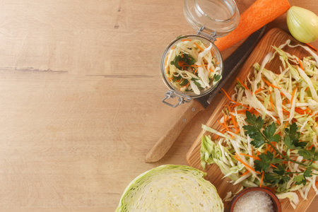 Cabbage lies on a wooden board with carrots, onions and herbs. Preparing to cook cabbage dishes.Copy spaceの写真素材
