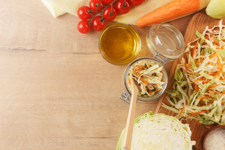 Cabbage lies on a wooden board with carrots, onions, herbs and cherry tomatoes. Preparing to cook cabbage dishes. copy spaceの写真素材