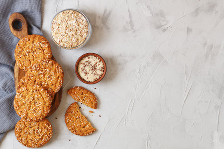 Oatmeal cookies with sesame seeds and flax seeds on a gray background with a jar of oatmeal and textiles. copy spaceの写真素材