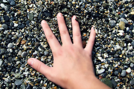 Hand laying on a pebble close upの写真素材
