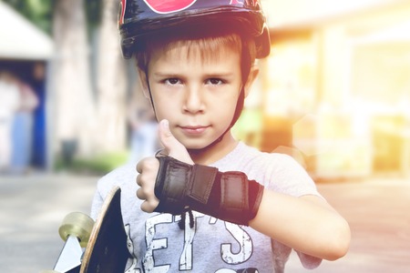 Boy with skateboard showing thumbs up sign outdoors.toningの写真素材