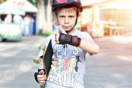 Boy with skateboard showing thumbs up sign outdoors.toningの写真素材