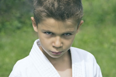 Portrait of a serious boy in a kimono on a green backgroundの写真素材