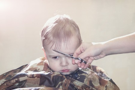 One year old boy for the first time makes the haircut in a Barber shop and sits with an air of importanceの写真素材