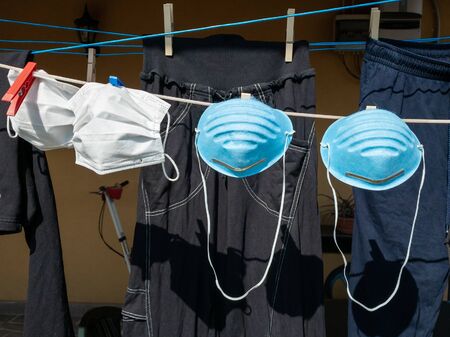 Mantova, Italy May 11th 2020: Protective medical masks hanging on a rack outdoor together with clothes, after being hand washed, concept of coronavirus, shortage of masksの写真素材