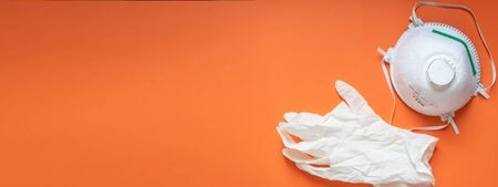 banner with a medical mask FFP2 or FFP3 and gloves on an orange plain background with copy space on...