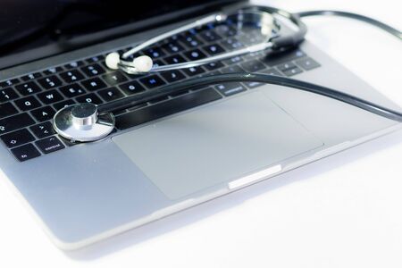 close up of a laptop with a stethoscope laying on it on white background, computer virus conceptの写真素材