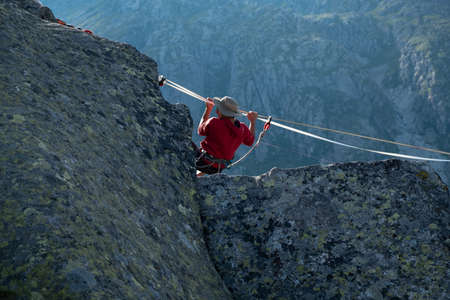 Lago Nero, Pinzolo, Italy - 2020 july 18th: young boy with red hoodie and hat practicing slackline...