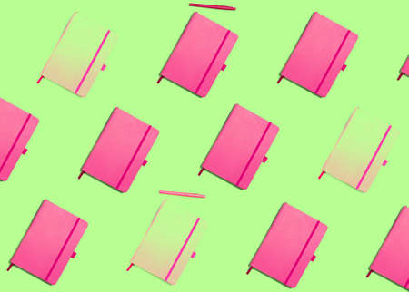 Pattern with pink notebooks on green background, pop style, vivid colors, concept of school, creativity, stationaryの写真素材