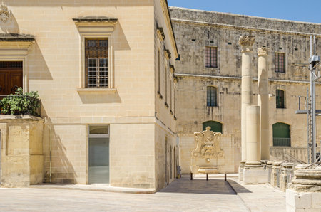 Ordnance street with the ruins of the demolished Opera House at Pjazza Teatru Rjal (Royal Theater Square) with the baroque water well at the wall of the House of the Annona in Valletta, Maltaの写真素材