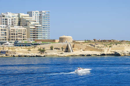 Tigne Point with Fort Tigne with its circular keep, built by the Order of Saint John, one of the oldest polygonal forts in the world, and modern residential buildings in Sliema, as seen from Valletta, Maltaの写真素材