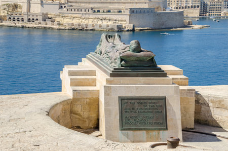 View of the War sculpture by Michael Sandle from the Siege Bell War Memorial or Malta Siege Memorial at the entrance to the Grand Harbor in Valletta, toward Fort St. Angelo and Birgu, an old fortified city in the South Eastern Region of Malta.のeditorial素材