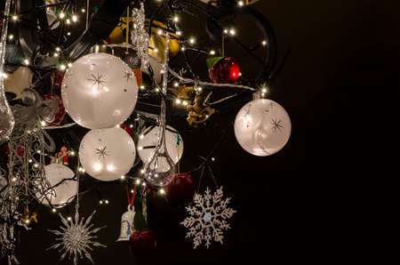 Illuminated Christmas baubles and Christmas tree decoration, lights, ornaments in a shape of a snowflake, bell, angels, applesの写真素材