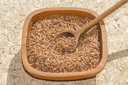 Old wheat species - grain-like triangular buckwheat seeds - in a rustic wooden shell with a wooden spoon. Because seeds are eaten and rich in complex carbohydrates, it is referred to as a pseudocereal. Rich source of protein, dietary fiber, 4 B vitamins and several dietary minerals. Buckwheat is approved for the Gluten Free diet.の写真素材
