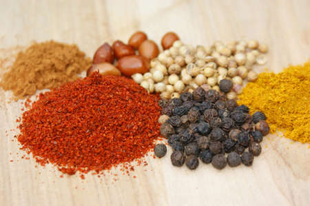 spicies on a wooden plate: chilli, pepper, coriander, curry, cinnamon, nutsの写真素材