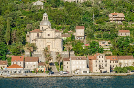 Prcanj. The town's waterfront with a long line of stone villas and the most impressive feat of architecture in Prcanj - the Birth of Our Lady church, designed by a Venetian architect Bernardino Maccaruzzi. The church has a monumental baroque facade with Corinthian and Doric columns.の写真素材