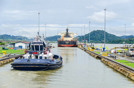 Panama City, Panama - November 4, 2017: Bulk Carrier KINGFISHER just passed through the Miraflores Locks with the help of a tugboat and electric locomotives or mules exiting the locks into the Miraflores Lake of Panama Canal.のeditorial素材