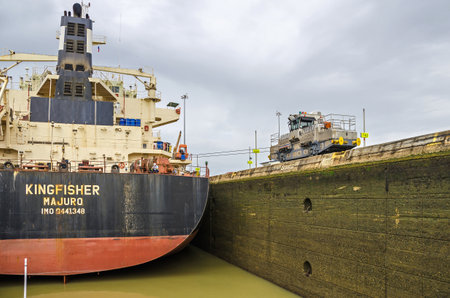 Panama City, Panama - November 4, 2017: Bulk Carrier KINGFISHER currently sailing under the flag of Marshall Islands in the Miraflores Locks, ready to lift with the help of the electric locomotive or mule maneuvering it through the chamber of Panama Canalのeditorial素材