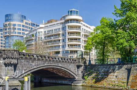 Berlin, Germany - April 22, 2018: Banks of the river Spree with the office building "Spreebogen", former interior ministry, and a part of the stone bridge Moabiter Bruecke or Bear Bridge with its bear sculptureのeditorial素材