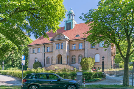 Berlin, Germany - June 3, 2021: Architectural monument former Town Hall Nikolassee with fire station and charging station with parked electric car being chargedのeditorial素材