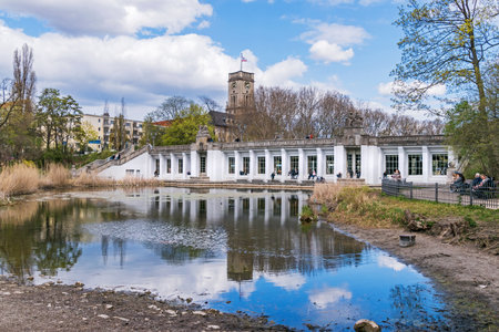Berlin, Germany - April 25, 2021: Garden monument Rudolph Wilde Park with the duck pond and the Carl-Zuckmayer bridge with the above-ground subway station Rathaus Schoenebergのeditorial素材