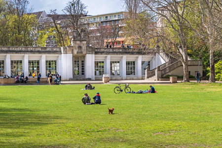 Berlin, Germany - April 25, 2021: Playgrounds of the Rudolph Wilde Park with people enjoying the spring and the architectural monument Carl-Zuckmayer bridge with the above-ground subway station Rathaus Schoenebergのeditorial素材