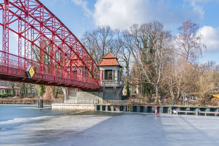 Berlin, Germany - February 19, 2021: Heritage-protected steel truss Haven bridge (Sechserbruecke) over the frozen stream Tegeler Fliess with its pavilion-like gate on the western tip of today's Humboldt Islandのeditorial素材